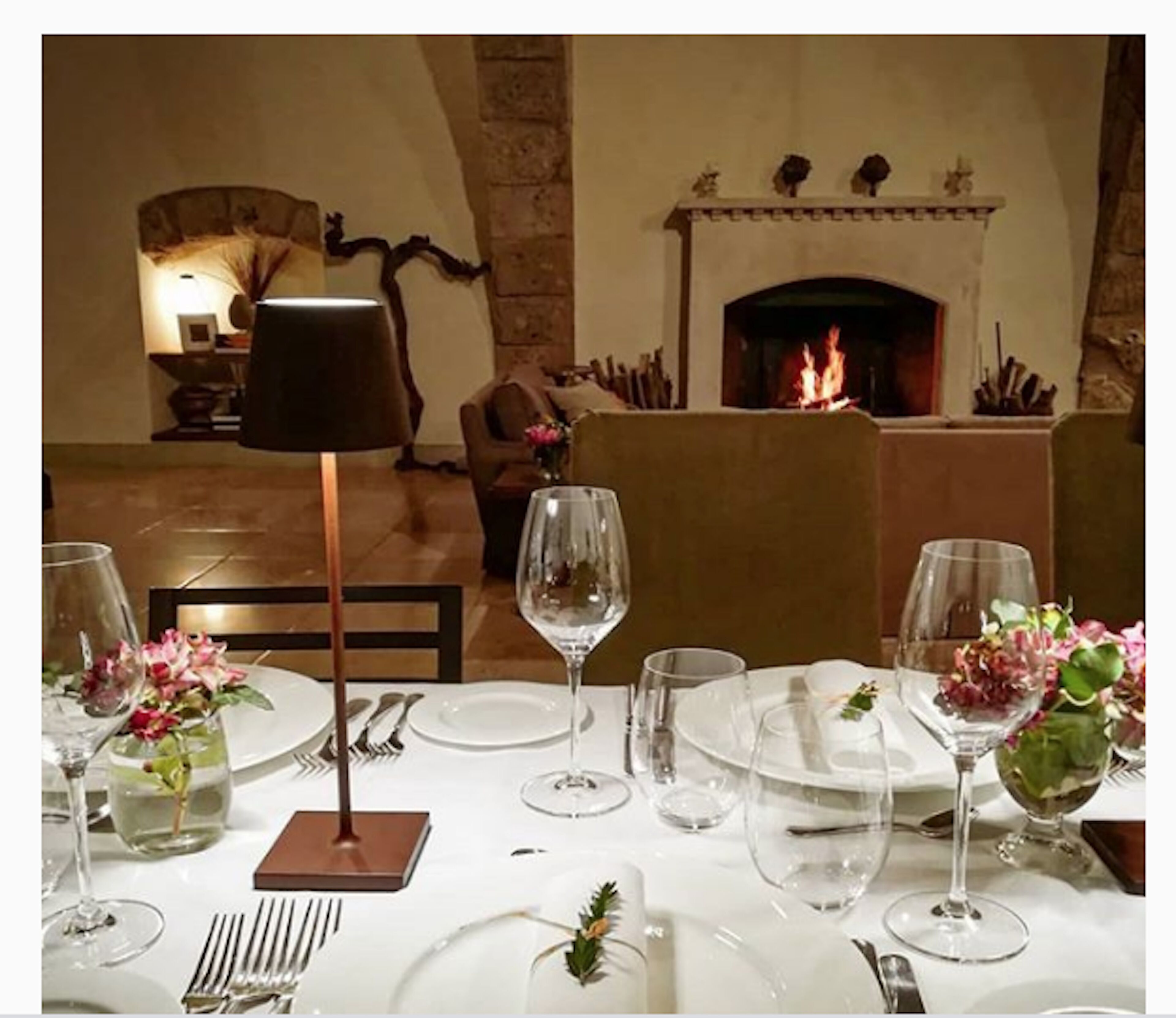 A dining table set for a meal with a fireplace in the background.
