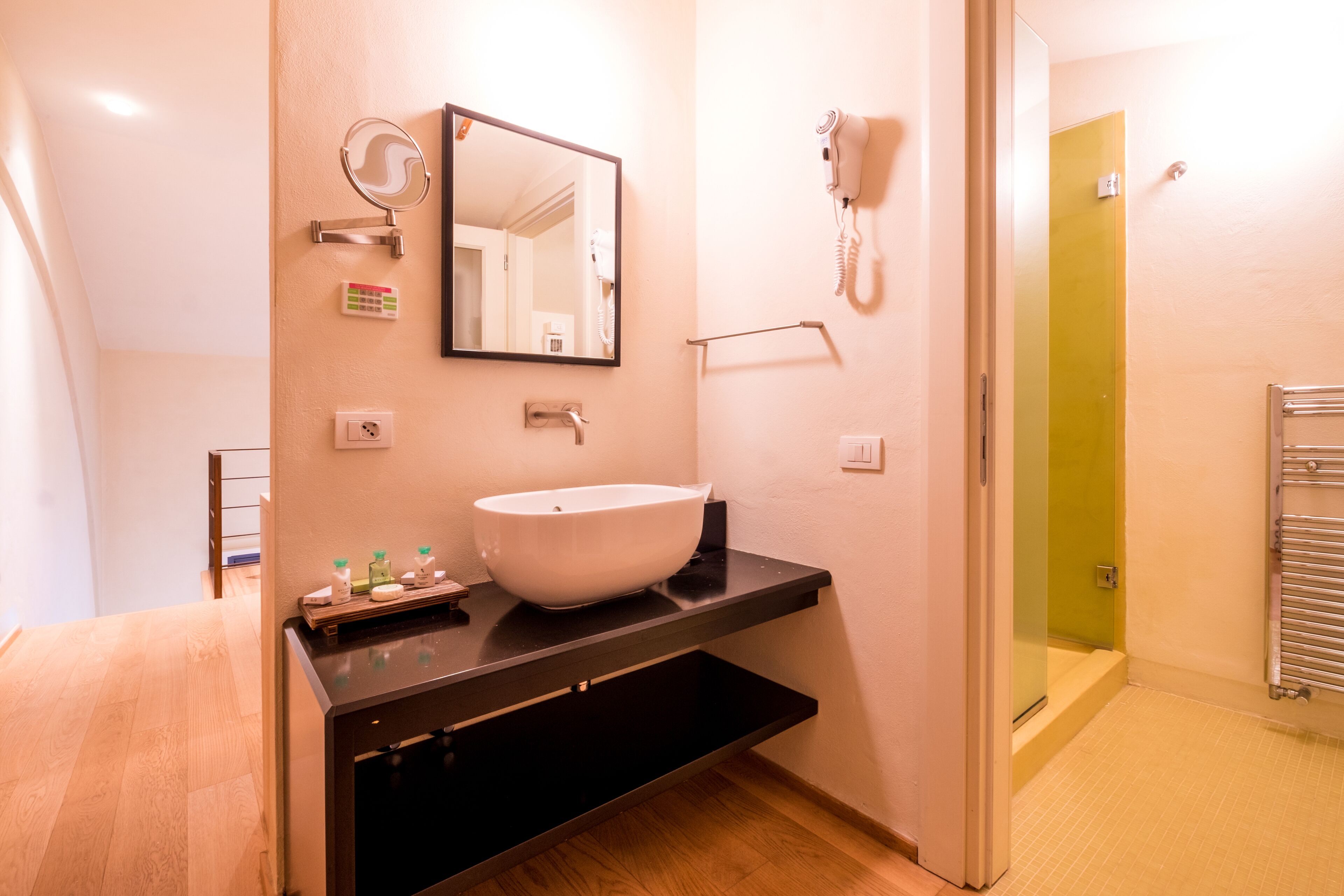 Une salle de bain moderne avec un grand lavabo blanc, un miroir, un sèche-cheveux et un porte-serviettes.
