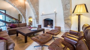 A spacious living area with leather sofas, a coffee table, and a fireplace.