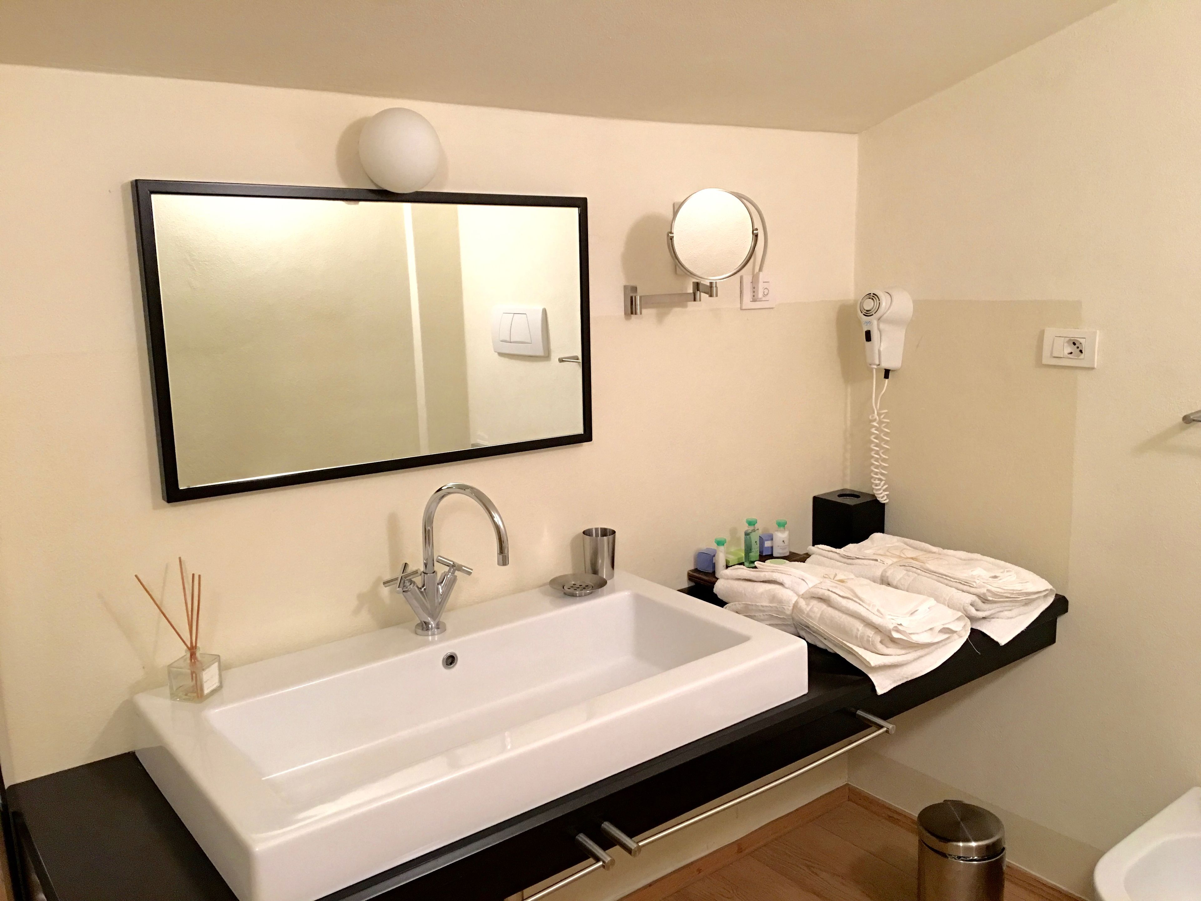 A bathroom with a white sink, a mirror, a hairdryer, and a towel rack.