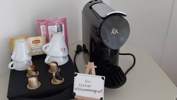 A coffee machine, a white teapot, Lipton tea bags, and a sign in German.