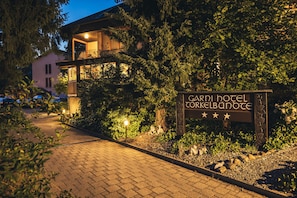 A hotel entrance with a sign reading "GARDI HOTEL CORKELBANOTE" and a paved pathway leading to the building.