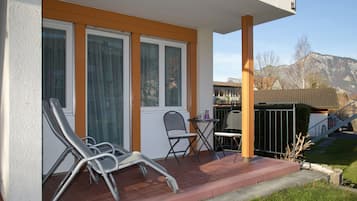 A balcony with two lounge chairs, a small table, and a chair.