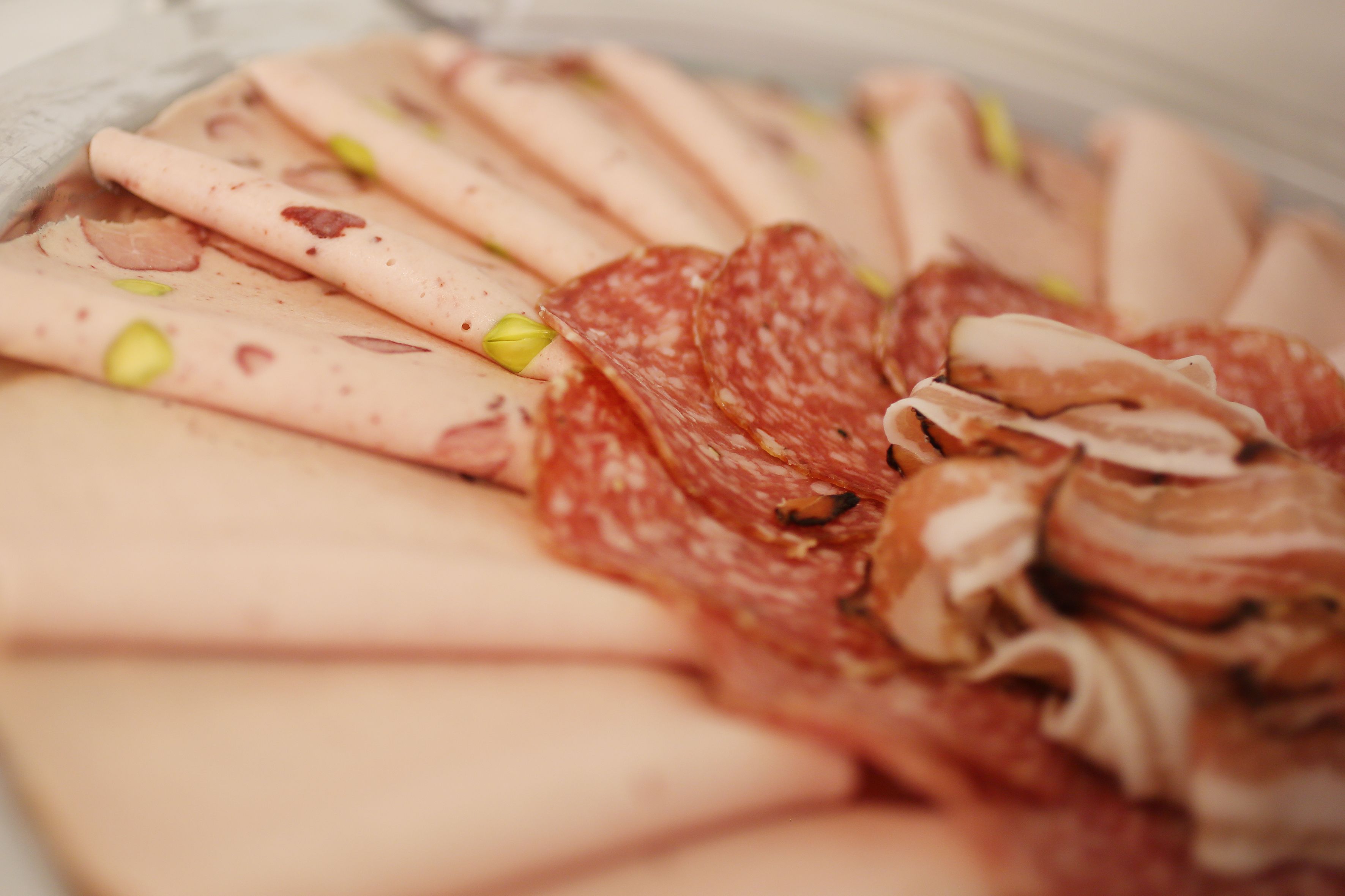 A variety of sliced meats including salami and possibly prosciutto, arranged on a plate.