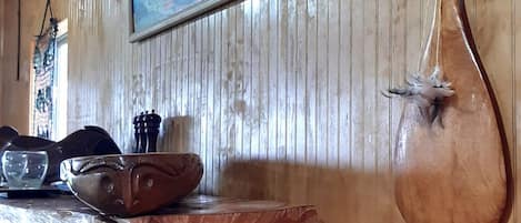 Un interior de madera con un muro de madera, un cuadro y una escultura de madera.