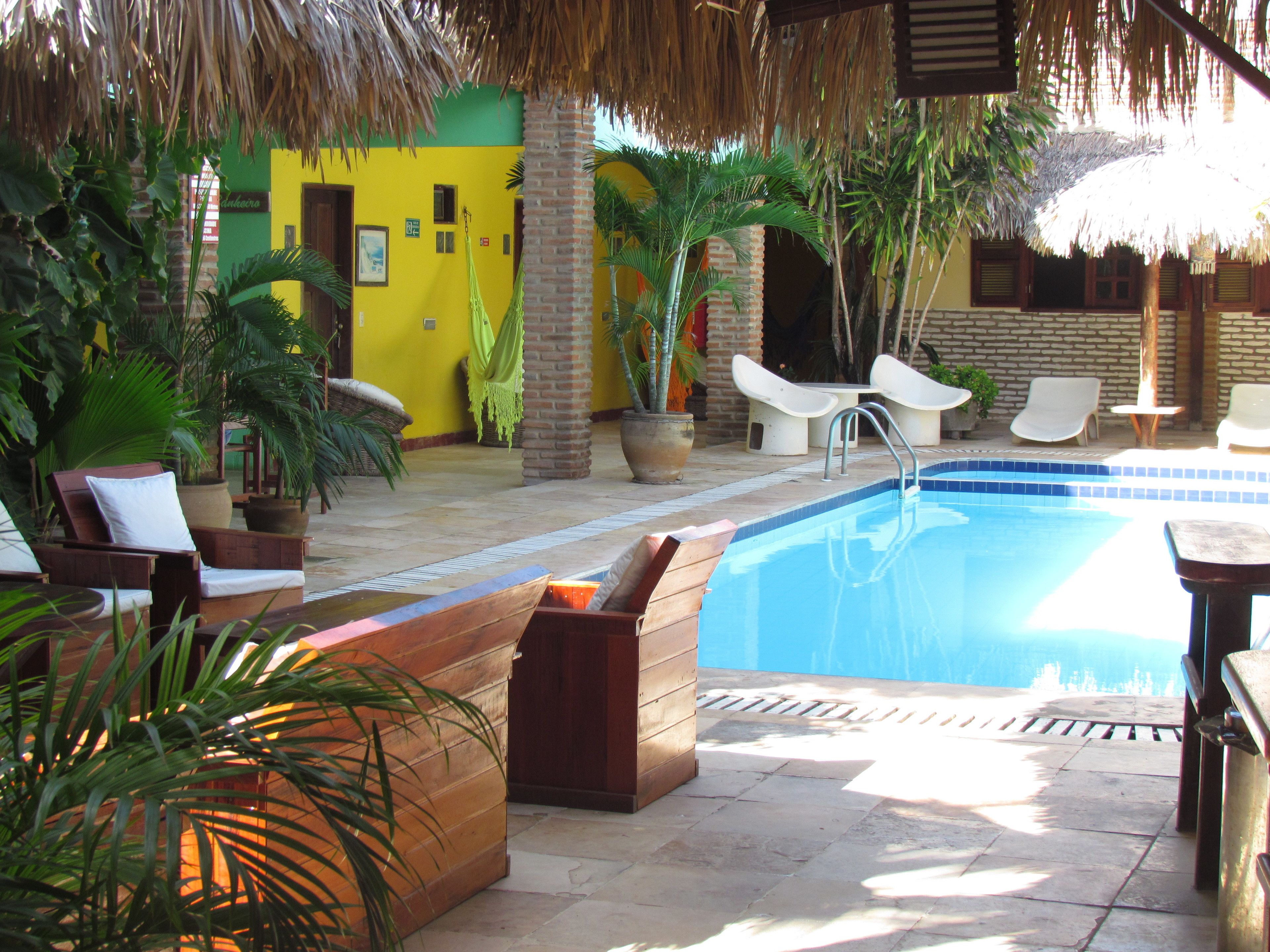 A pool area with lounge chairs, a hammock, and potted plants.