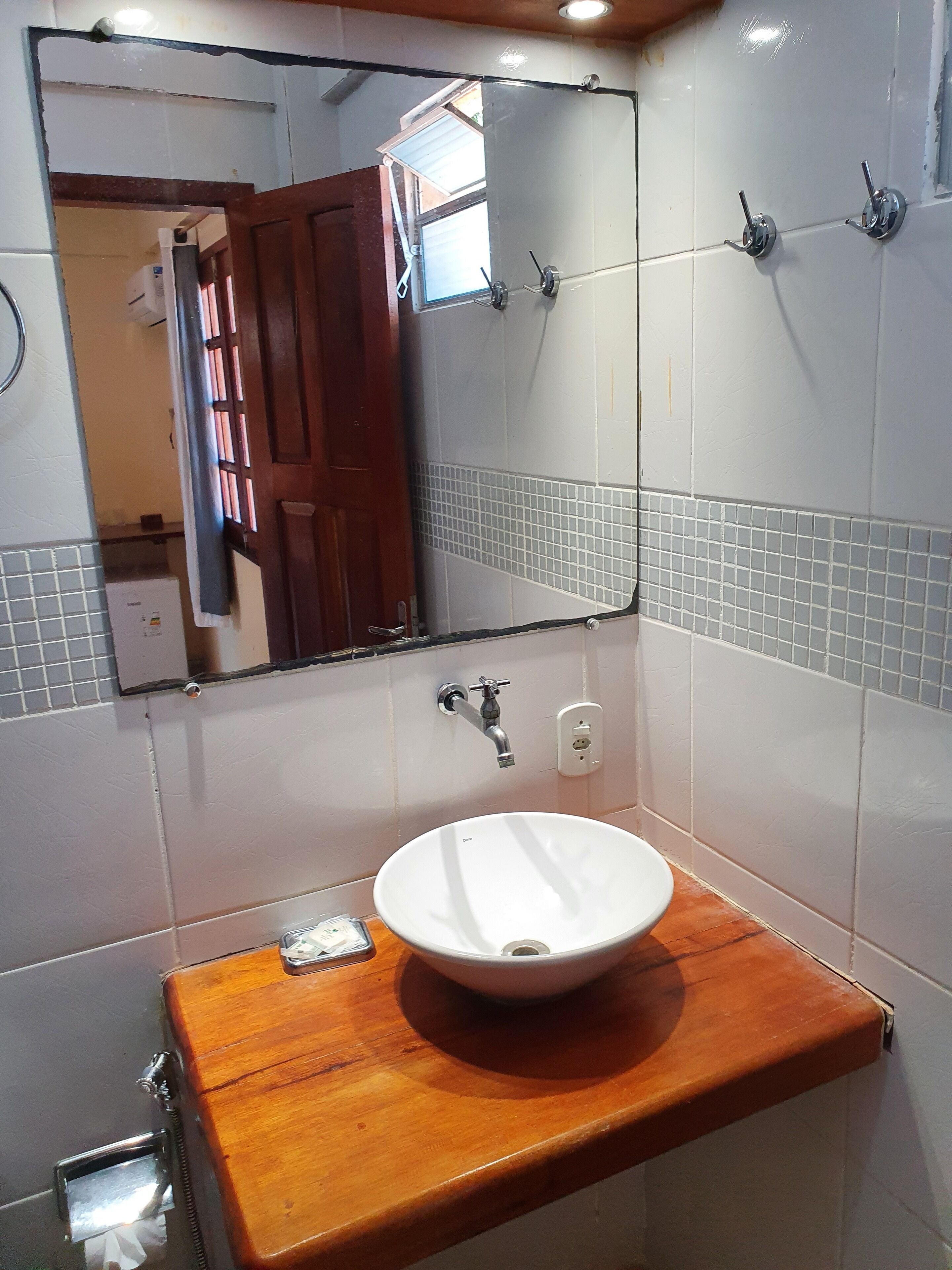 Un baño con lavamanos blanco, encimera de madera y un espejo encima.