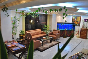A living room with a sofa, armchairs, a coffee table, and a fish tank. - Candles Hotel (Wadi Musa)