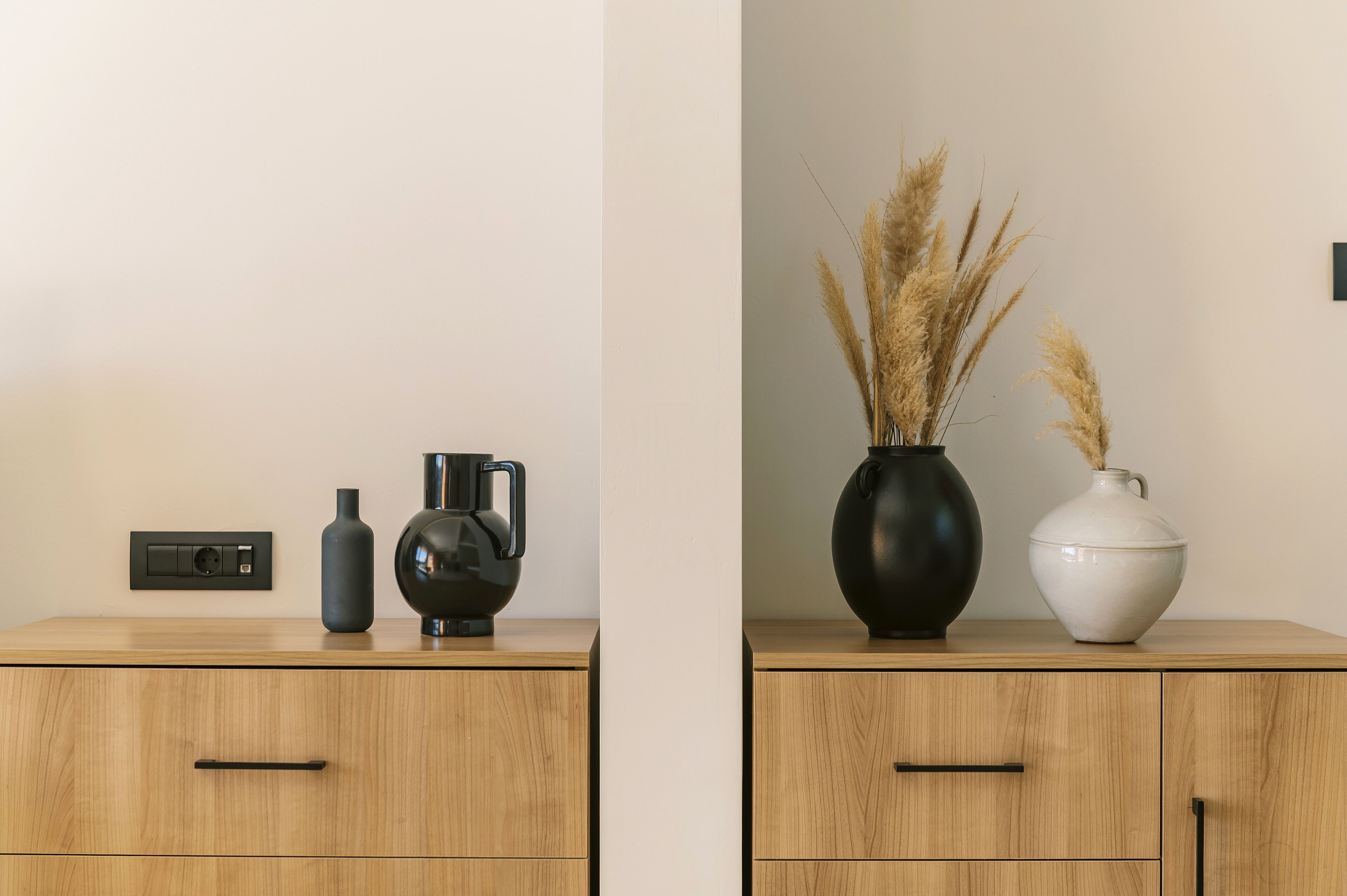 Twee houten kasten met zwart-wit vazen en een zwarte waterkoker erbovenop.