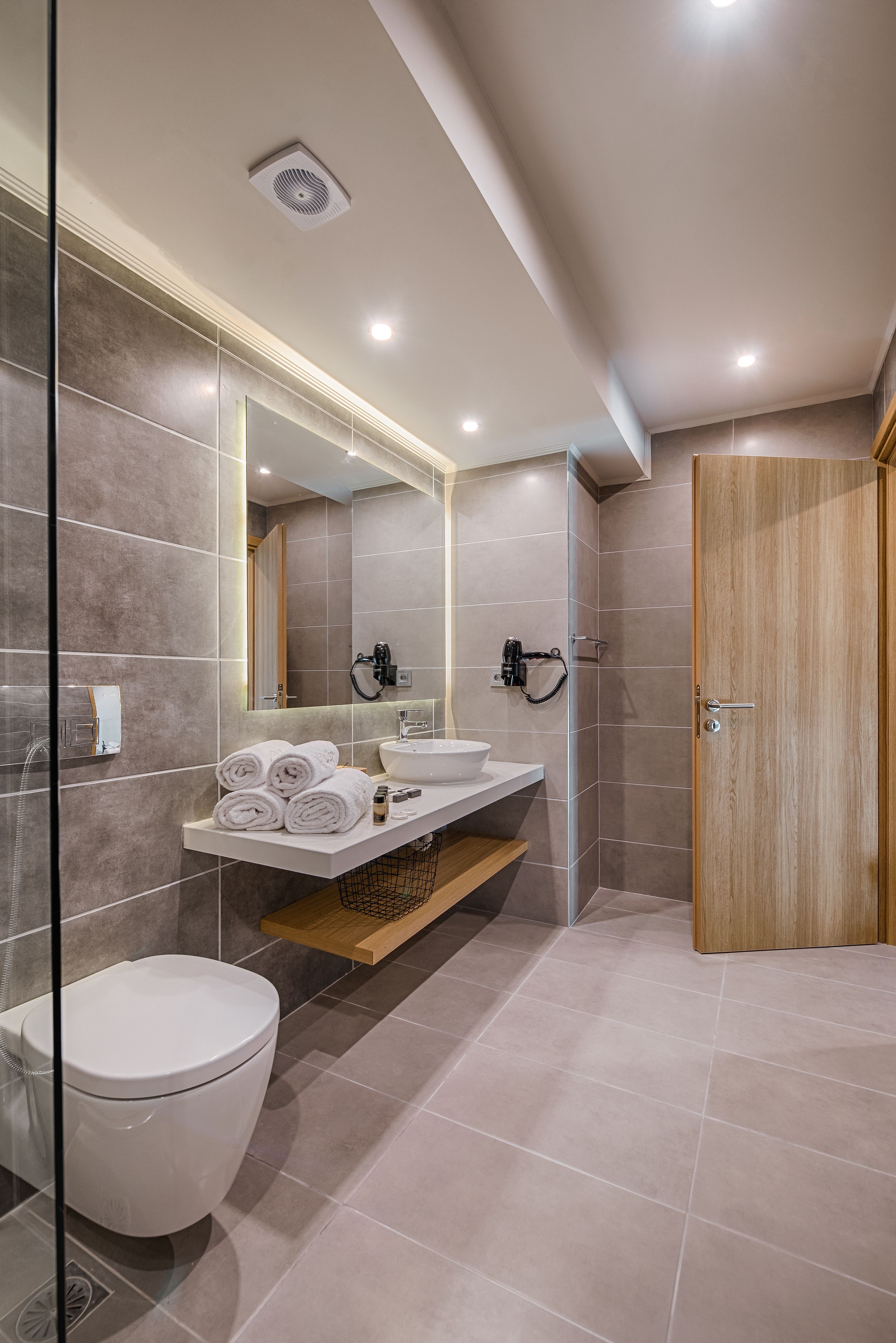 A modern bathroom with a toilet, sink, and mirror.