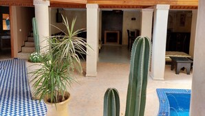 A spacious indoor area with a pool, cacti, and a fireplace. - Riad Andalib (Fes)