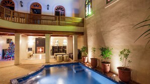 A pool area with a wooden deck, potted plants, and a Christmas tree. - Riad Andalib (Fes)