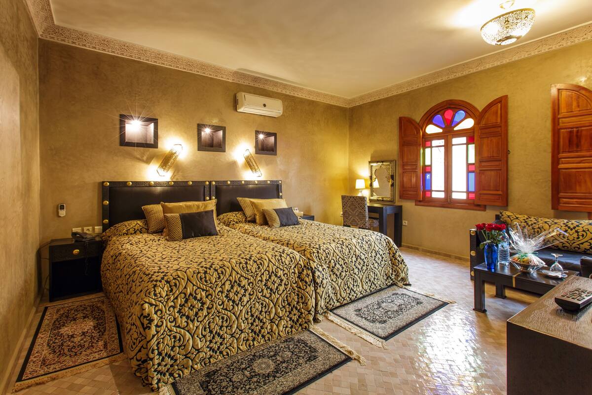 A hotel room with two beds, a sofa, a coffee table, and a decorative mirror.