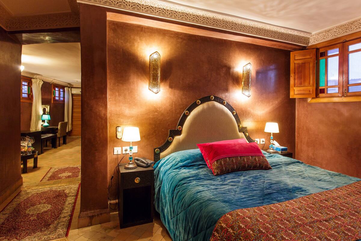 A bedroom with a large bed, two bedside lamps, and a nightstand with a phone.