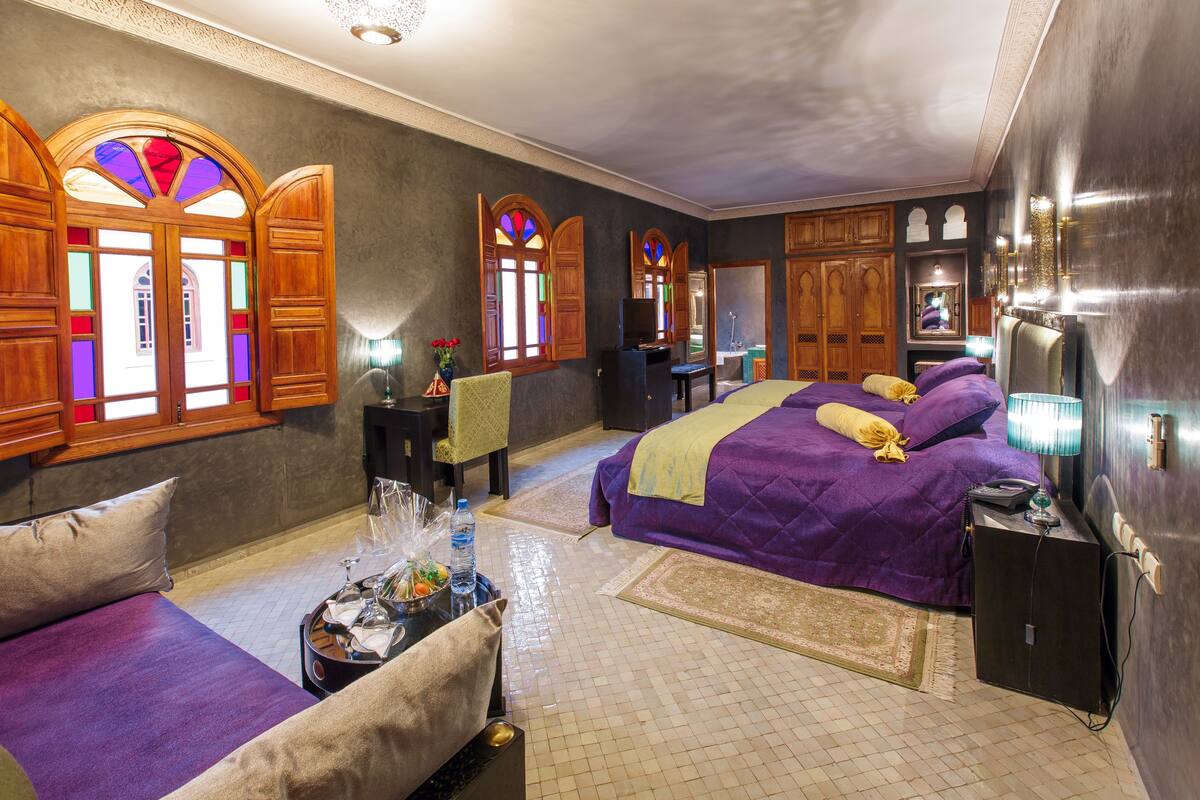 A hotel room with a large bed, a sitting area, and a desk.
