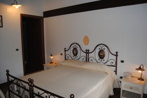 A bedroom with a bed, two bedside tables, a nightstand, a lamp, a telephone, and a door. - Hotel Il Dito e la Luna (Ripa Teatina)