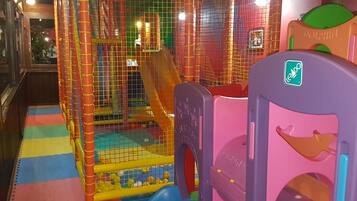 A children's play area with a slide and a ball pit, enclosed by a safety net.