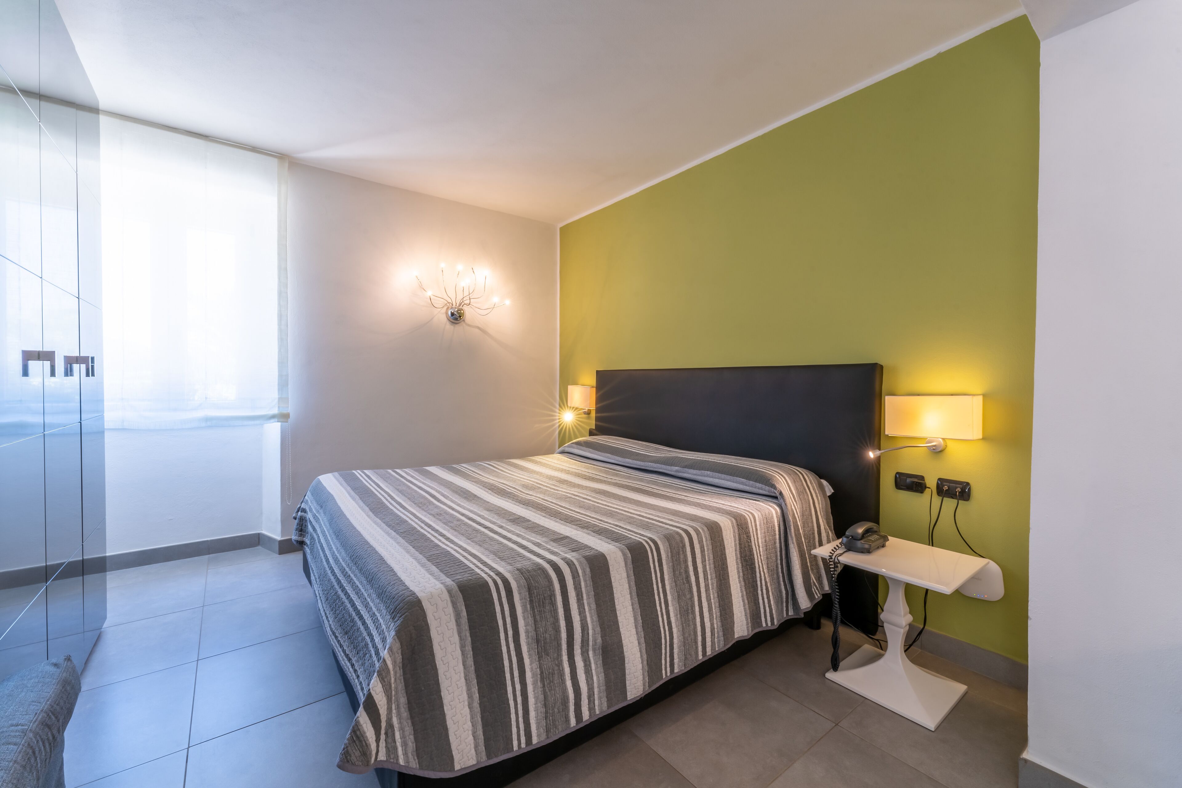 Une chambre moderne avec un grand lit, des lampes de chevet et une table de chevet avec un téléphone.