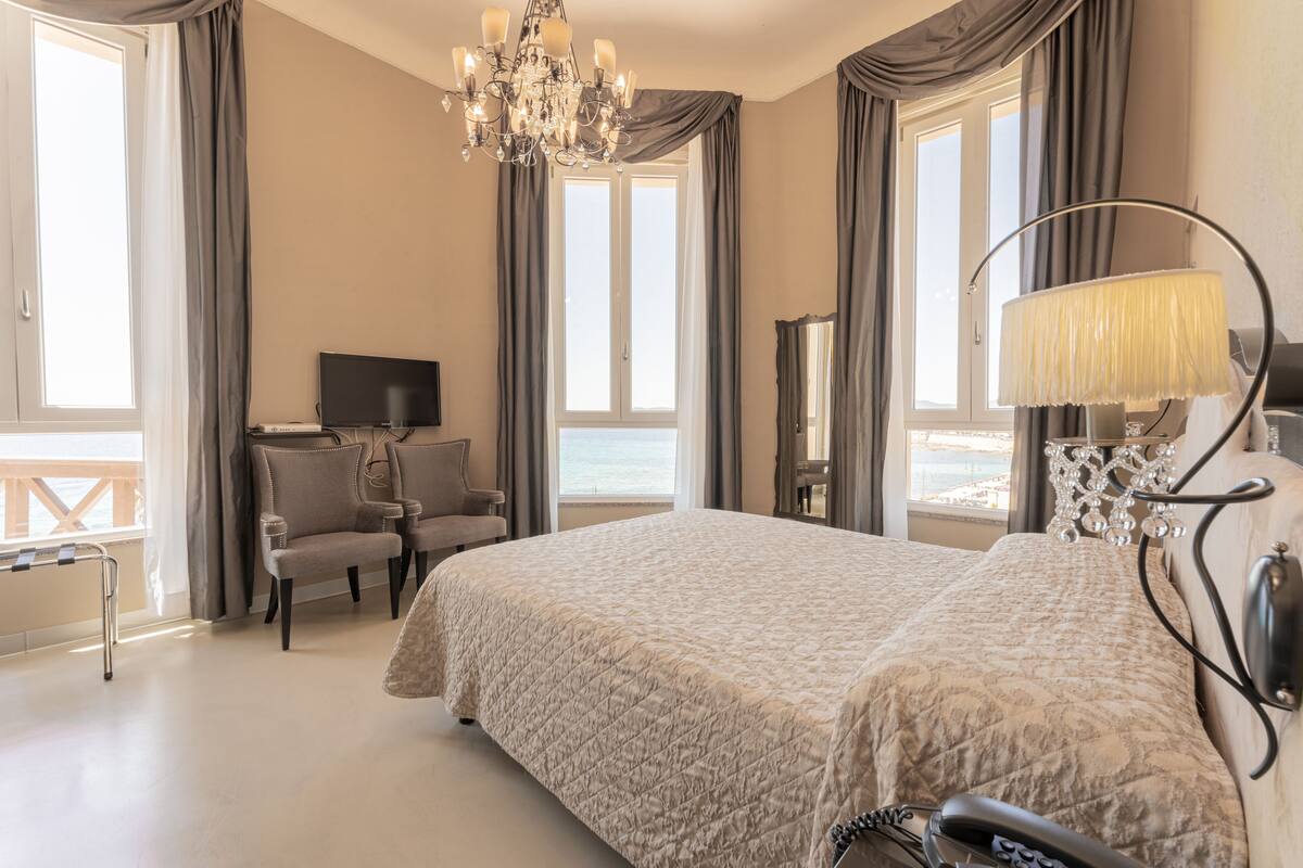 Habitación de hotel con una cama grande, televisión, una silla y vista al mar.