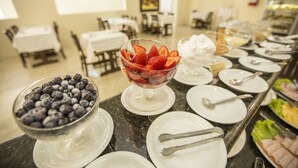 Un buffet avec des bols remplis de fruits rouges et des assiettes avec des couverts.