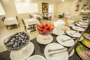 A buffet setup with bowls of berries and plates with cutlery.