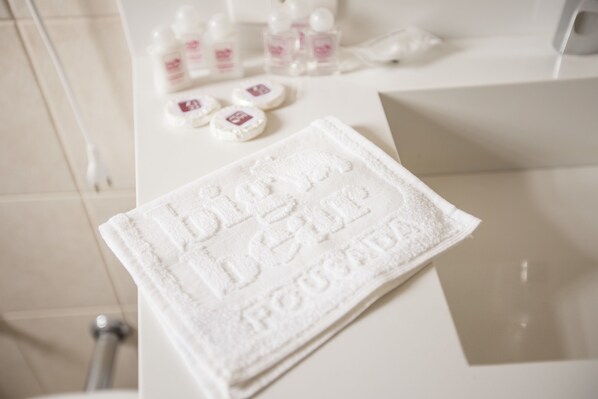 A bathroom with a white towel on a counter, a bottle of lotion, and a soap dish.