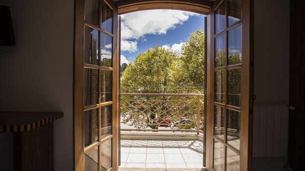Un balcon ouvert donnant sur des arbres et un ciel dégagé.