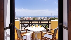 Un balcón con mesa y sillas, con vistas a una zona costera con edificios y cielo despejado.