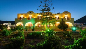 Un hotel con fachada simétrica, varios balcones y un árbol en el centro.