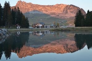 Hotel ved søen med bjergene i baggrunden, og et spejlbillede i vandet.