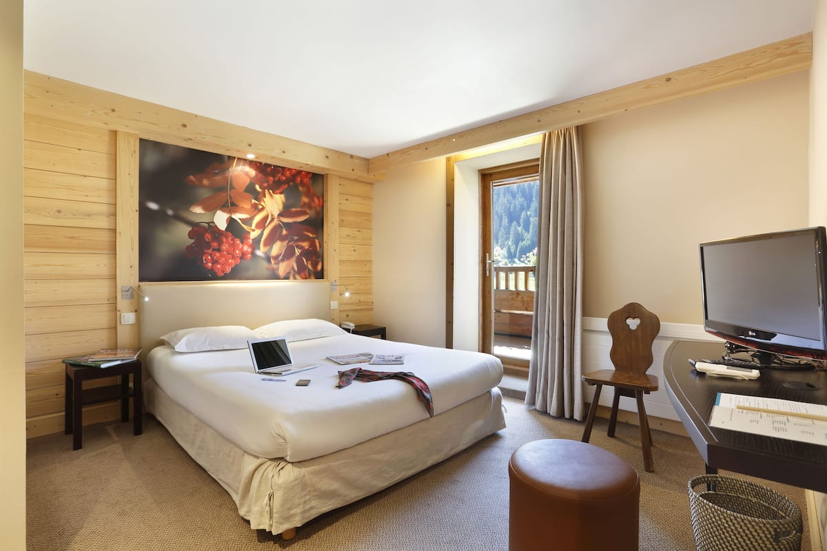 Habitació d'hotel amb un llit gran, un escriptori amb ordinador, una cadira i una televisió.