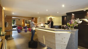A reception area with a wooden reception desk, a seating area with chairs, and a decorative vase with flowers.
