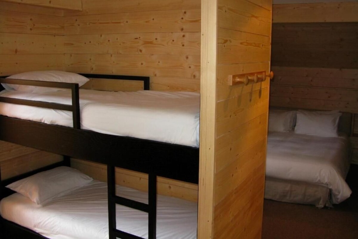 Habitación con literas, paredes de madera y una puerta.