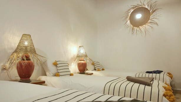 Ein Schlafzimmer mit zwei Betten, gestreifter Bettwäsche und dekorativen Lampen.