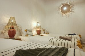 A bedroom with two beds, striped bedding, and decorative lamps.