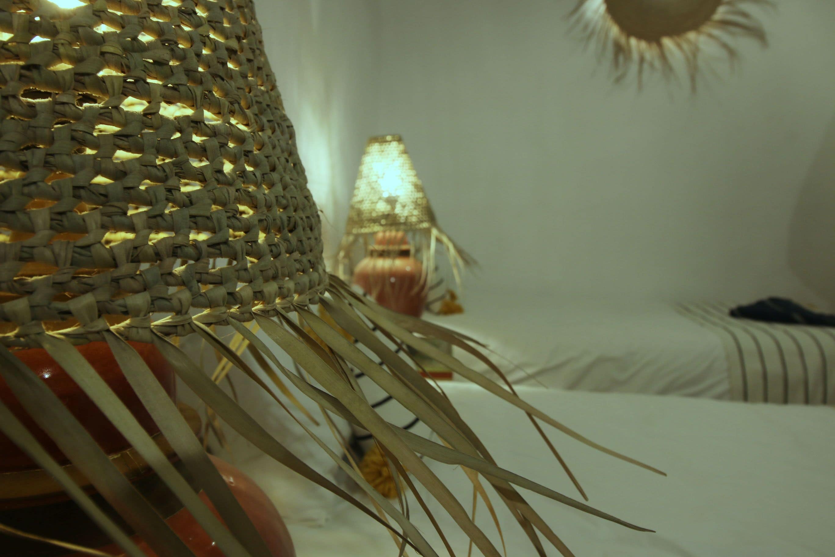 A room with a bed, a woven basket, and a lamp.