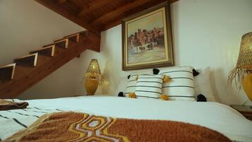 Un dormitorio con una cama, un cuadro, una lámpara y una escalera.