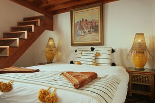 Una camera da letto con un letto, un quadro, due lampade e una scala.