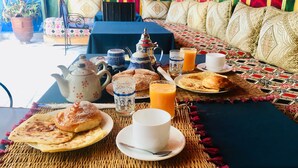 Ein Frühstückstisch mit verschiedenen Speisen, einer Teekanne, Tassen und einem Orangensaftkrug.