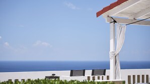 A terrace with white furniture, a view of the sea, and a white pergola. - Nakou Village (Ierapetra)