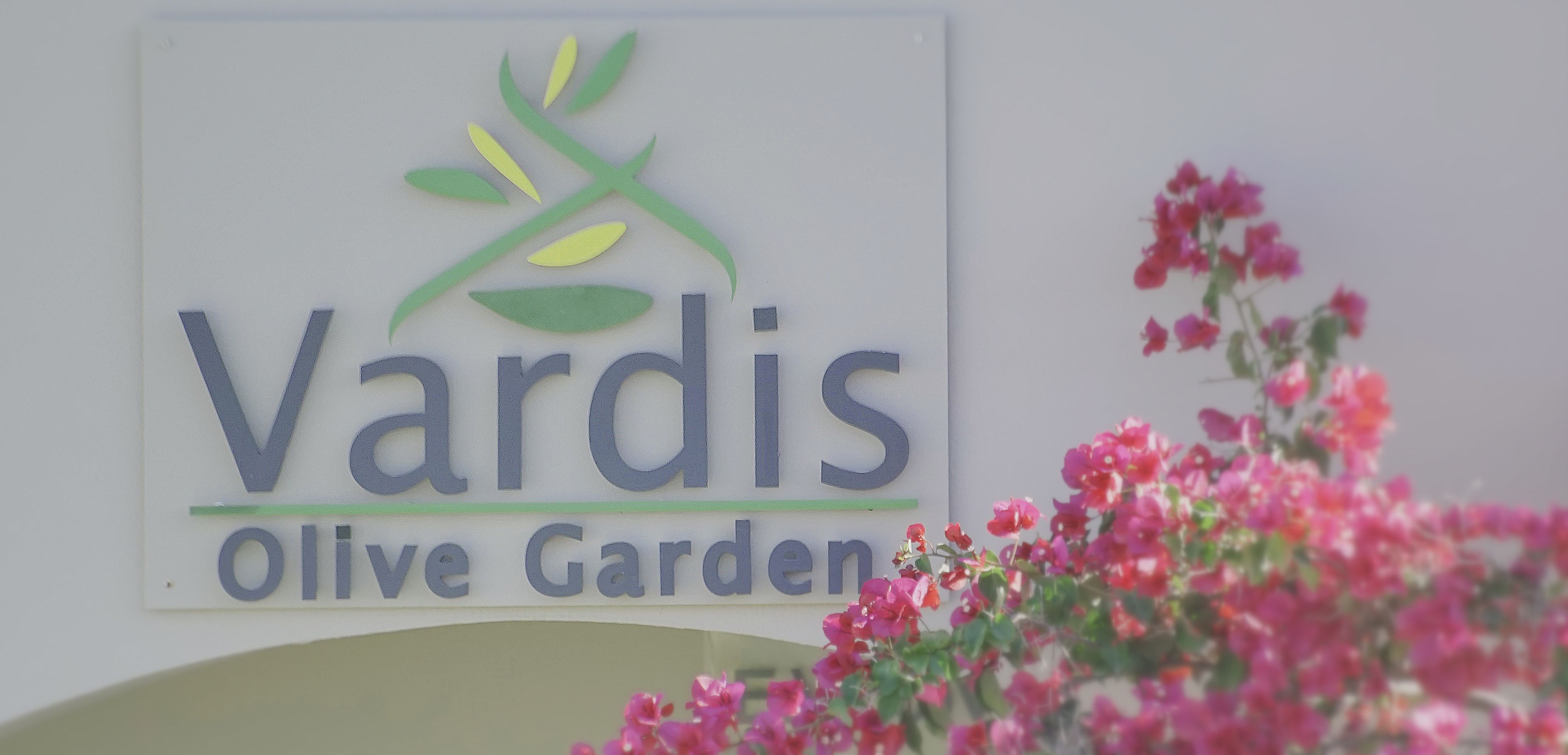 Um sinal para 'Vardis Olive Garden' com um logotipo com ramos e folhas de oliveira.