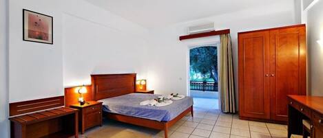 Un dormitorio con cama, mesitas de noche, un armario de madera y vistas al exterior.