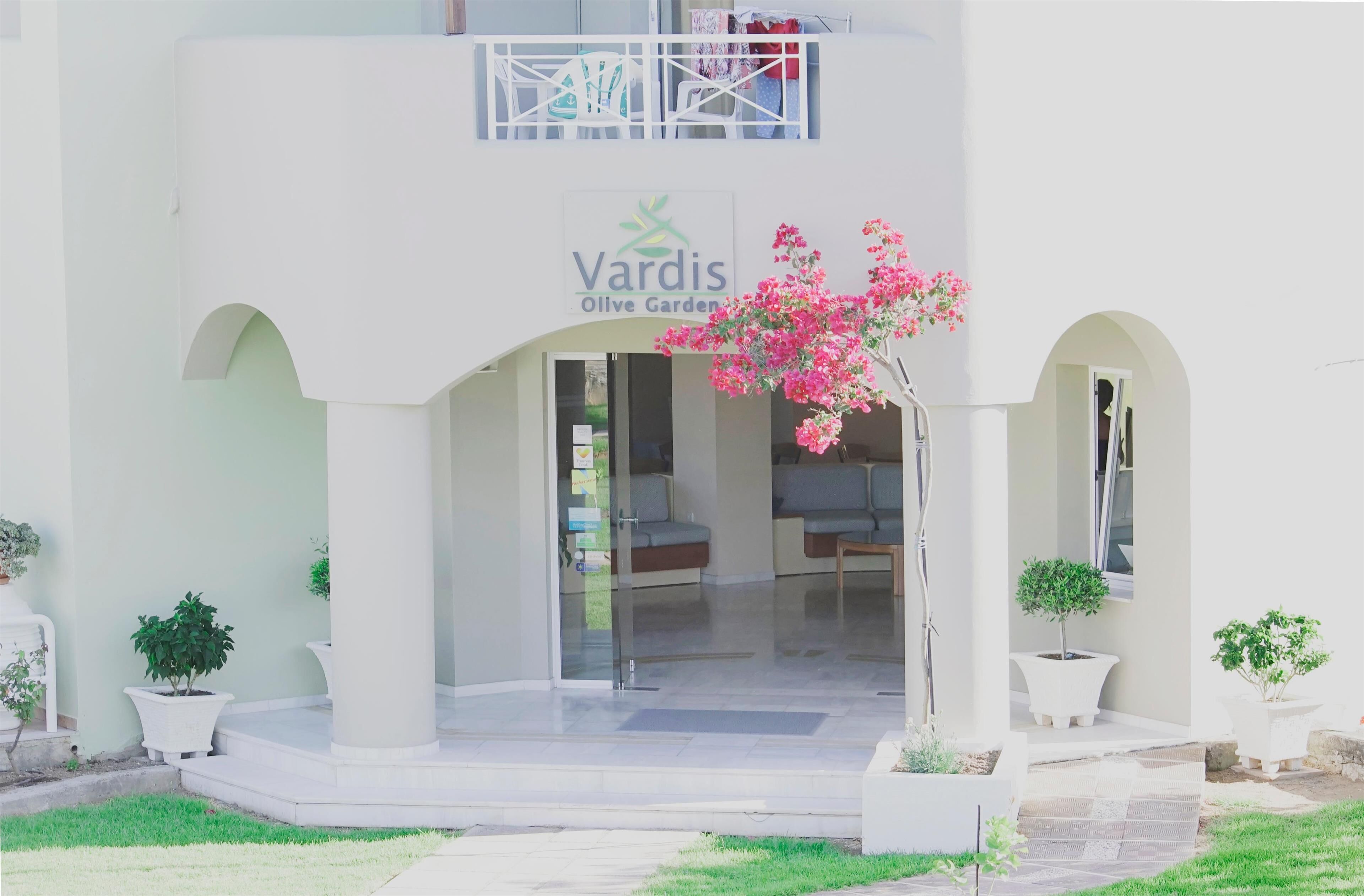 A building with a sign reading "Vardis Olive Garden" and a covered entrance with seating.