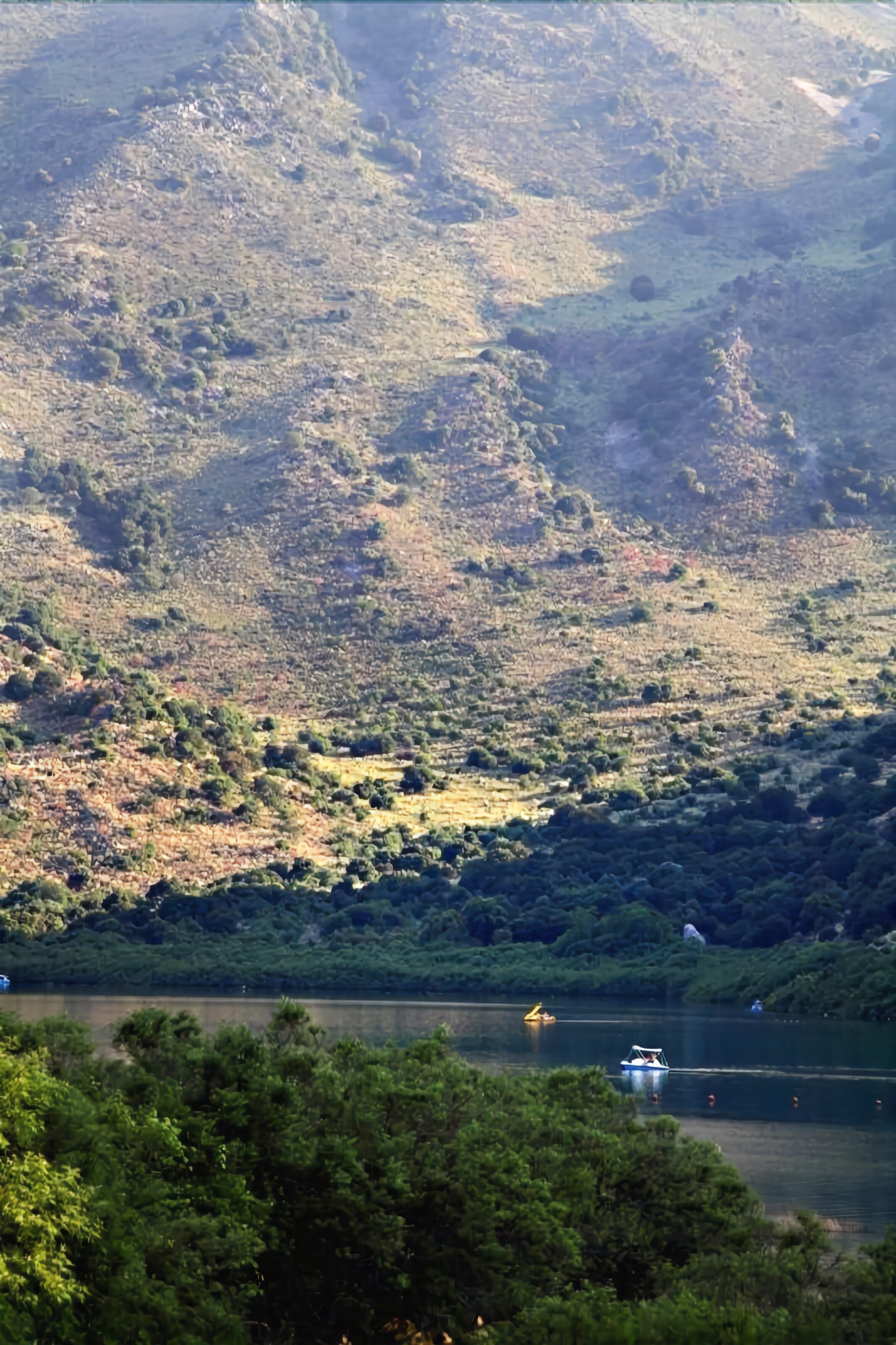 A lake surrounded by hills with a boat on the water.