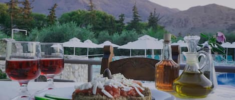 A table with a plate of food, two glasses of red wine, and a bottle of olive oil.