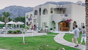 Ein Resort mit einem zentralen Poolbereich, umgeben von Gästezimmern mit Balkonen, vor einer Bergkulisse.