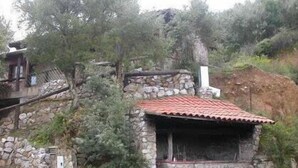 A stone building with a red-tiled roof, surrounded by trees and a stone wall. - Agriturismo La Quercia (Arbus)