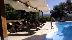 A poolside area with lounge chairs and a covered seating area. - Agriturismo La Quercia (Arbus)