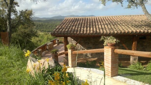 A rustic stone building with a tiled roof, surrounded by lush greenery and a mountainous backdrop. - Agriturismo La Quercia (Arbus)