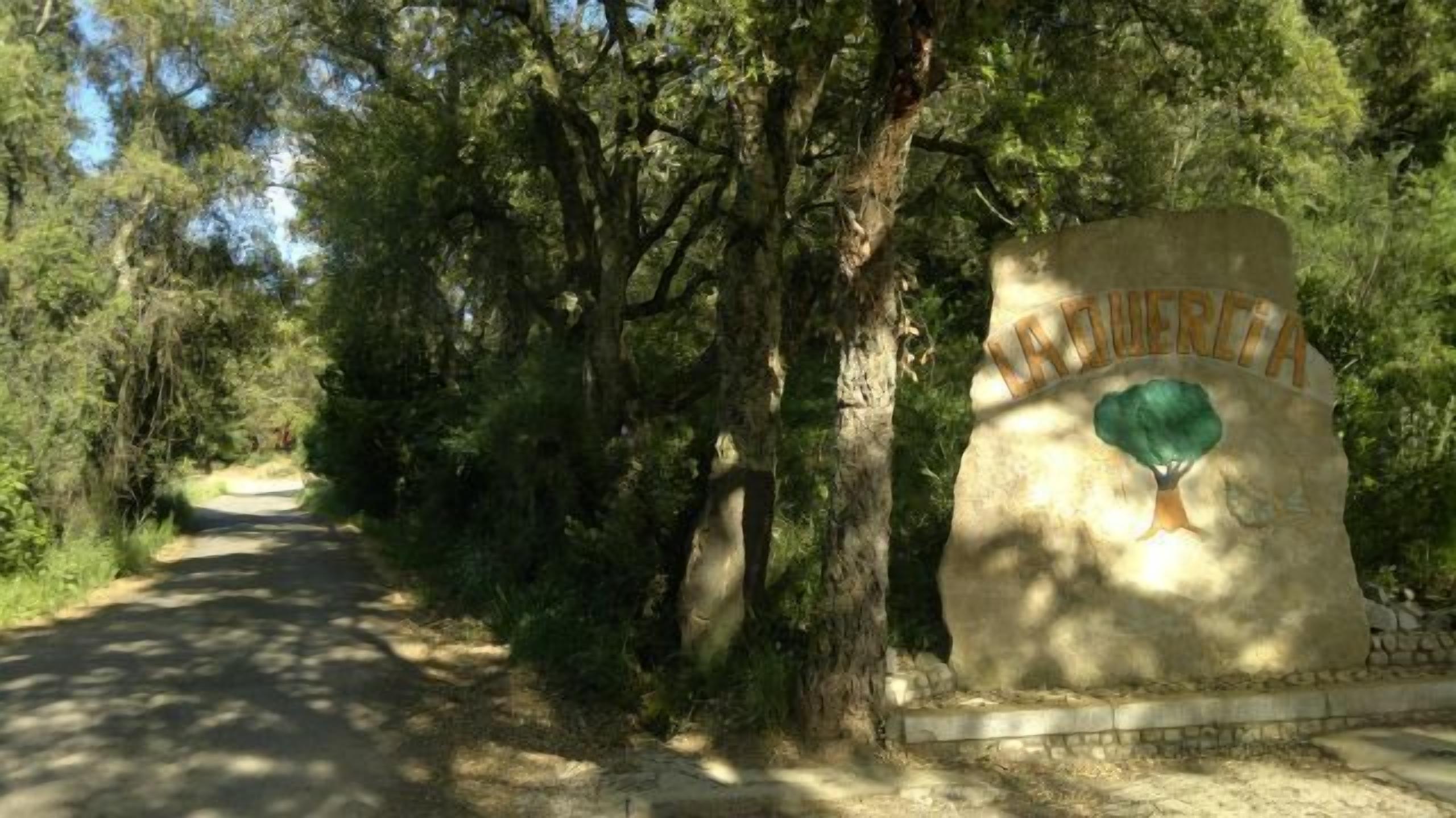 A sign with the name 'LAZARETTA' and a green emblem, surrounded by trees and a dirt path.